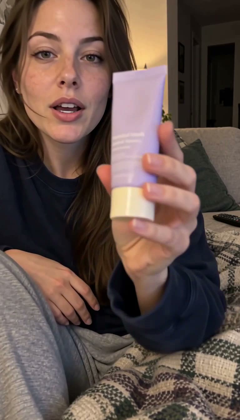 A creator on a sofa holding a lavender hand cream tube